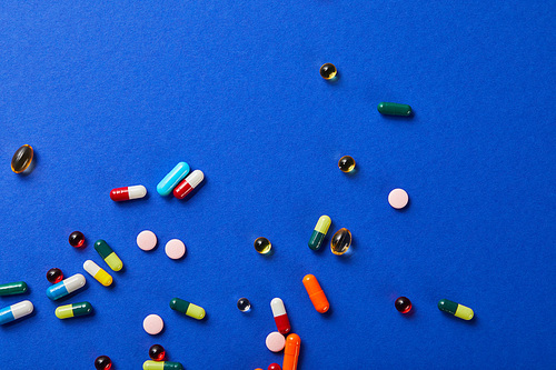 top view of various colorful scattered medical pills on blue surface
