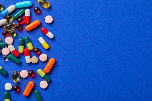 various colorful medical pills on blue surface