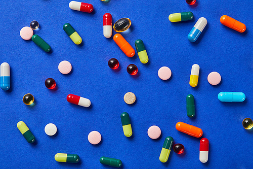 top view of different medical pills on blue background