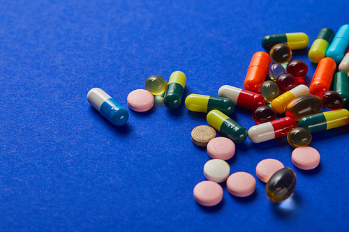 various colorful scattered medical pills on blue background