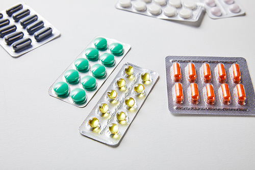 scattered blister packs with different pills isolated in white