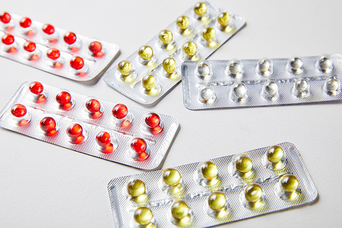 scattered blister packs with colorful transparent pills isolated in white