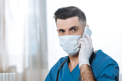 young doctor in medical mask and latex gloves talking on smartphone and 