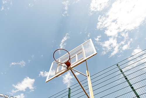 bottom view of basketball backboard under blue sky with clouds