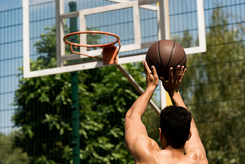 back view of basketball player throwing ball in basket at basketball court