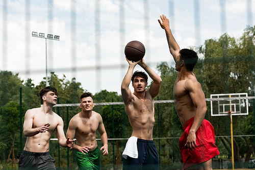 selective focus of shirtless sportsmen playing basketball at basketball court