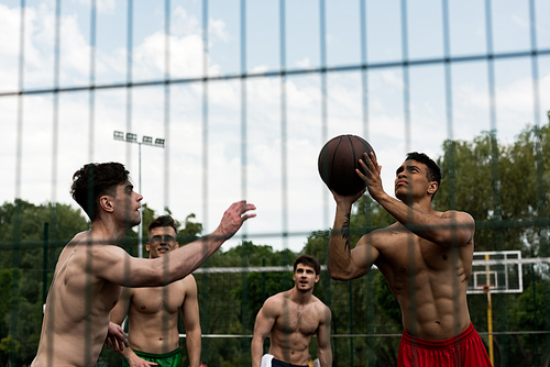 selective focus of shirtless sportsmen playing basketball at basketball court