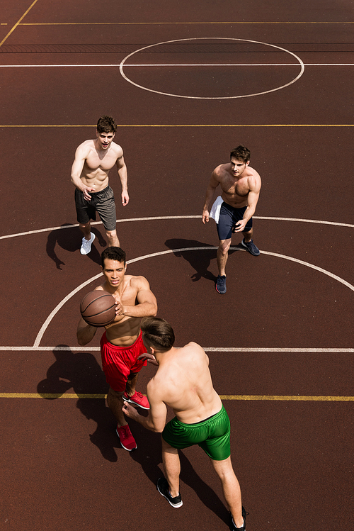 overhead view of four shirtless basketball players with ball at basketball court