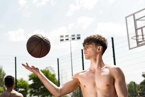 shirtless basketball player with ball at basketball court in sunny day