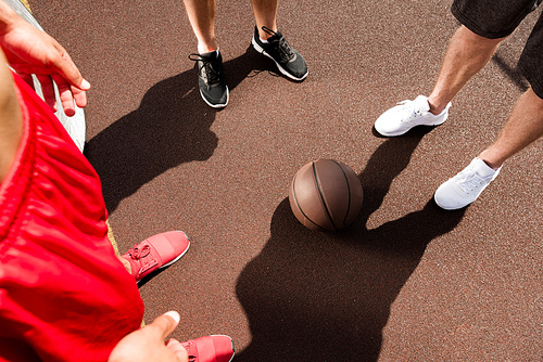 cropped view of three sportsmen with ball at basketball court