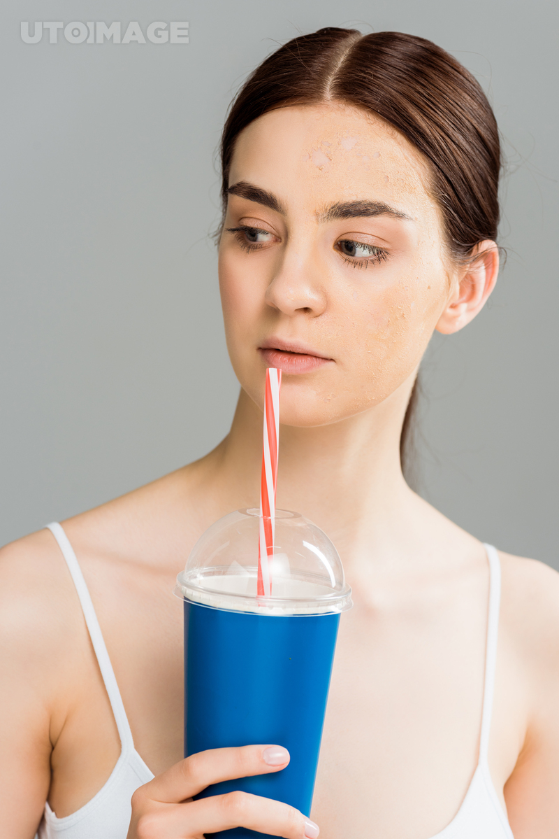 유토이미지 | young woman with problem skin holding plastic cup isolated on grey