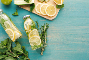 top view of detox drink in bottles with lemon and cucumber slices, mint and rosemary