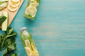 top view of detox drink in bottles with lemon and cucumber slices and mint