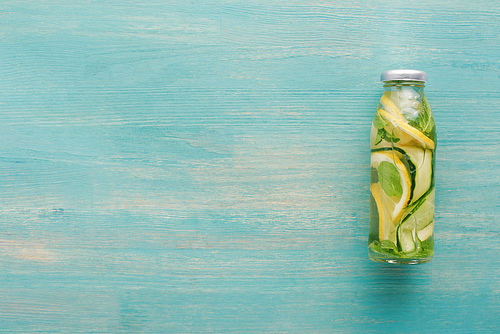 top view of detox drink in bottle with fresh lemon and cucumber slices and mint