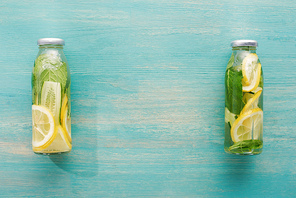 top view of detox drink in bottles with fresh lemon and cucumber slices and mint