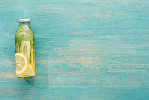 top view of detox drink in bottle with fresh lemon and cucumber slices and green mint