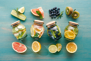 top view of detox drinks in jars with citrus fruits, berries and cucumbers