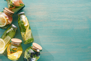 top view of detox fresh drinks in bottles and jars with fruits, s, herbs, berries and greenery