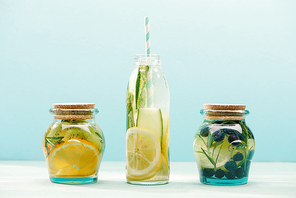 detox drinks in opened bottle with straw and jars isolated on blue