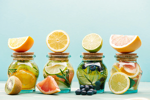 fresh detox drinks in jars with ingredients isolated on blue
