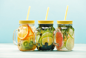 fresh organic detox drinks with berries, fruits and s in jars with straws isolated on blue