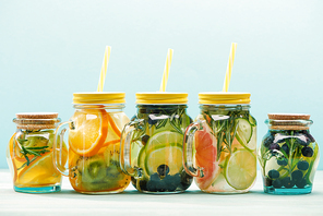 fresh detox drinks with berries, fruits and s in jars with straws isolated on blue