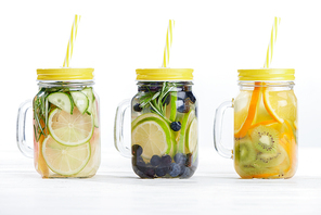 fresh detox drinks in jars with straws, fruits and berries on white background