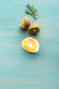 Top view of cut fruits and rosemary on blue textured surface