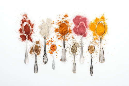 top view of colorful spices in silver spoons on white background