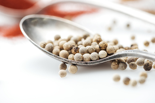 close up view of white pepper in silver spoon