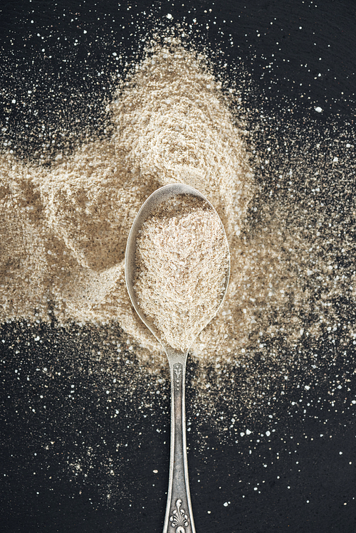 top view of garlic powder in silver spoon on black background