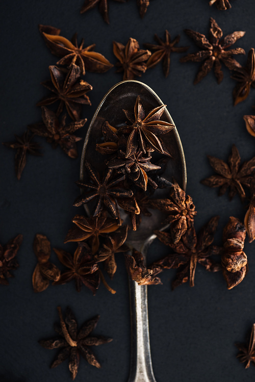 top view of anise in silver spoon on black background