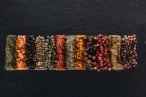 top view of traditional bright indian spices on textured black background