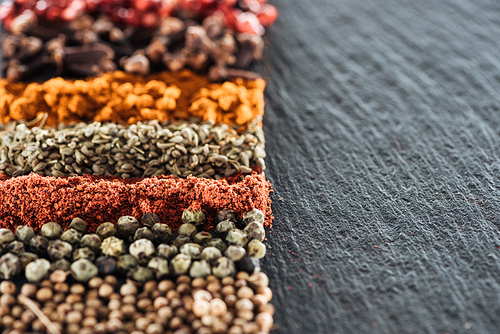 close up view of traditional bright indian spices on textured black background