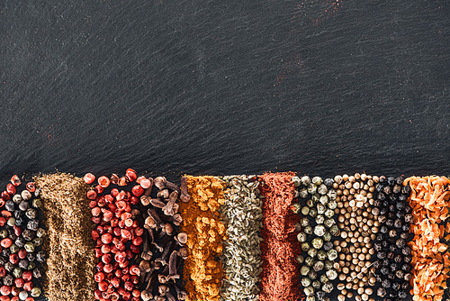 top view of traditional bright indian spices on textured black background with copy space
