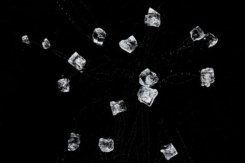 top view of scattered transparent refreshing ice cubes isolated on black