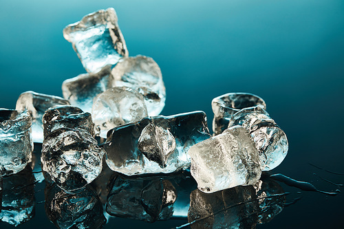 stack of transparent melting ice cubes on emerald background