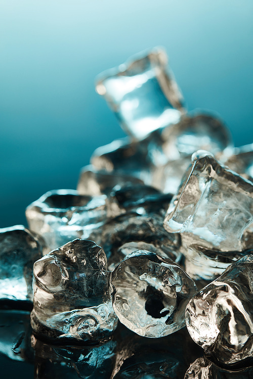 selective focus of transparent ice cubes on emerald background