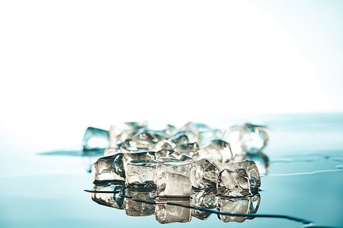 stack of transparent melting ice cubes on emerald and white background