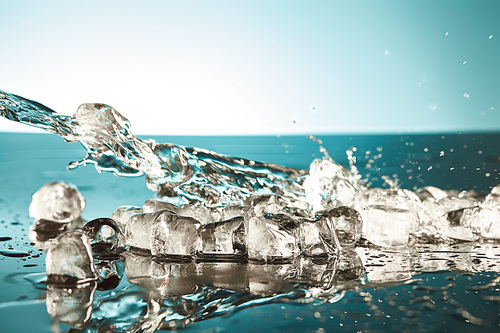 transparent melting ice cubes with splashing water on emerald and white background