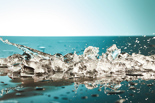 cool melting ice cubes with water splash on emerald and white background