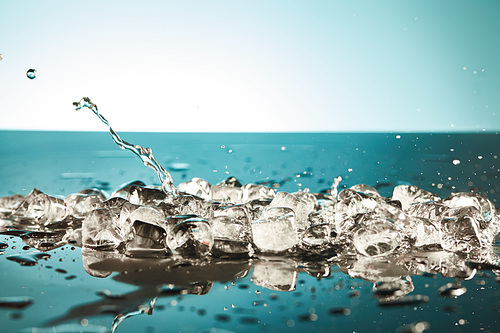 melting ice cubes and water splash on emerald and white background