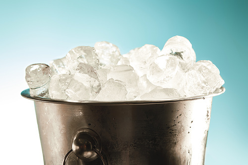 cool ice cubes in metal bucket on emerald and white background