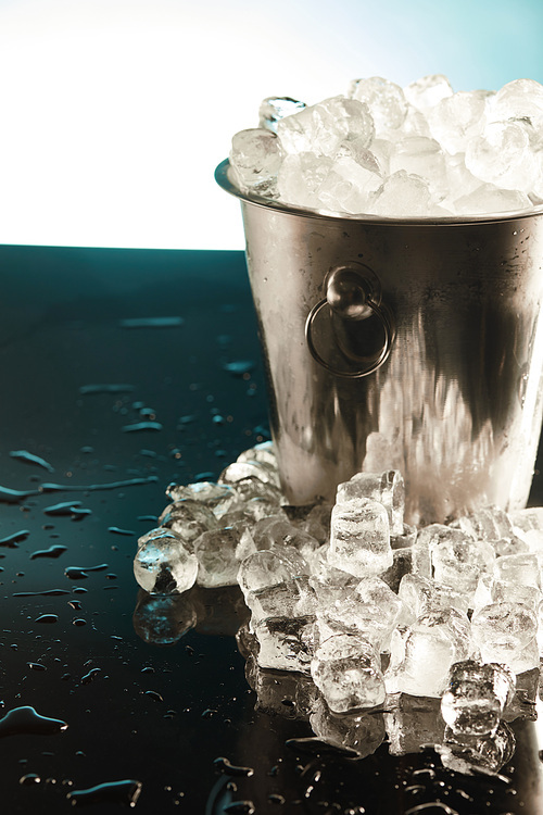 transparent ice cubes in metal bucket on emerald surface