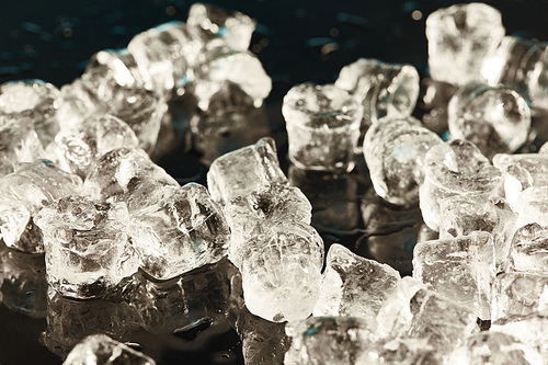 transparent cool ice cubes on black background with water drops