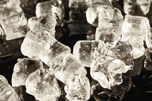 stack of transparent cool ice cubes on wet black surface