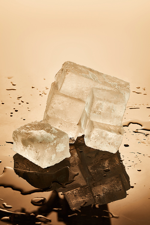 stack of transparent melting ice cubes on brown background