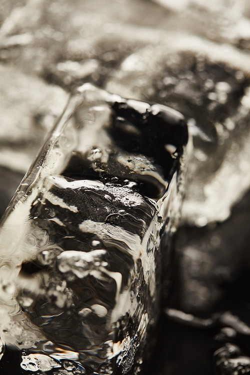 close up view of transparent wet textured ice cubes on black background