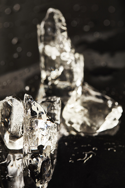 transparent melting ice cubes with drops on black surface