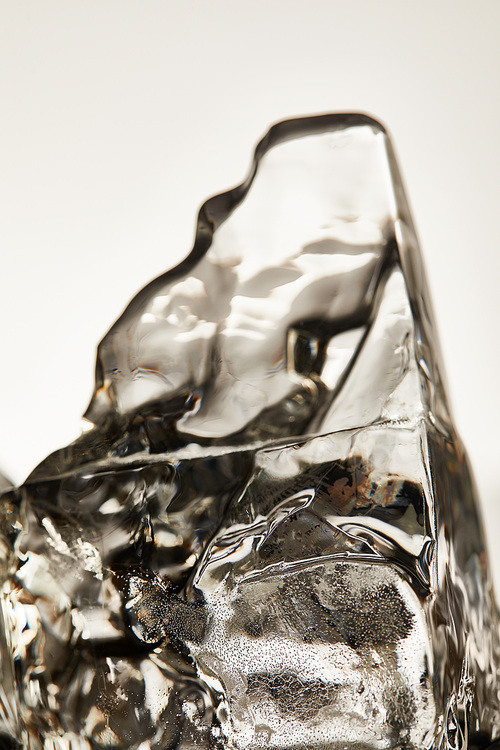 close up view of transparent melting ice cube isolated on grey